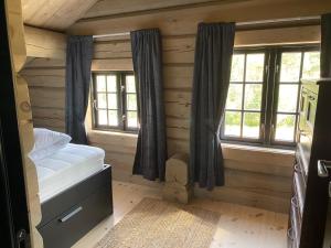 a bedroom with a bed and windows in a cabin at Koslig helårs hytte in Heimdal
