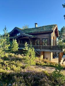 a large log house with a wrap around porch at Koslig helårs hytte in Heimdal