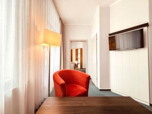 a room with a red chair and a table at Strandhotel Graal-Müritz in Graal-Müritz