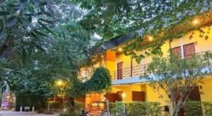 a yellow building with trees and lights in front of it at Wanarom Resort in Ban Maklua Kao