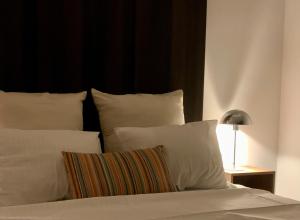 a bed with white pillows and a lamp on a table at PATERSHOF vakantieverblijf in Diest