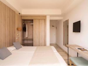 a bedroom with a large white bed and a tv at Ona Palmira Paguera in Paguera