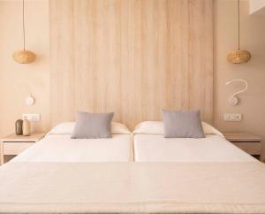 two beds in a room with white sheets at Ona Palmira Paguera in Paguera