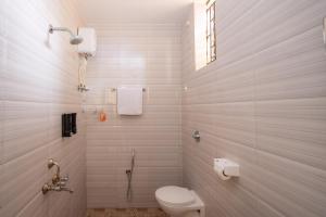 a white bathroom with a toilet and a shower at Palolem White House in Canacona +79 photos