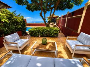 a patio with white chairs and a coffee table at Villa Zen - Tu oasis en el sur de Tenerife in Adeje