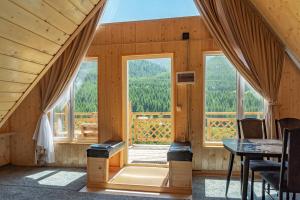 a room with a table and windows in a cabin at A-frame Sky in Karakol
