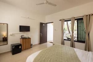 a bedroom with a bed and a flat screen tv at Palolem White House in Canacona
