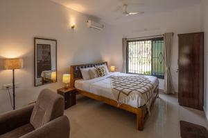 a bedroom with a bed and a chair and a window at Palolem White House in Canacona
