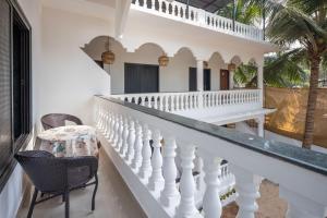 a white balcony with chairs and a table at Palolem White House in Canacona