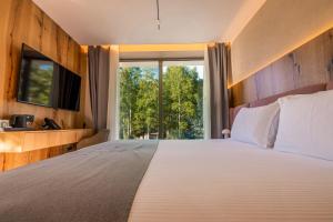 ein Schlafzimmer mit einem großen Bett und einem großen Fenster in der Unterkunft Pine Hotel & Spa Brezovice in Brezovica