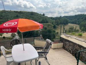 a table and chairs with an umbrella on a balcony at Appartement le Gallon in Langogne