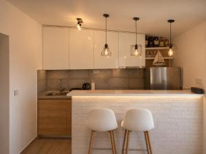 a kitchen with white cabinets and two white stools at VN Lux Apartments in Prijevor +1 photo
