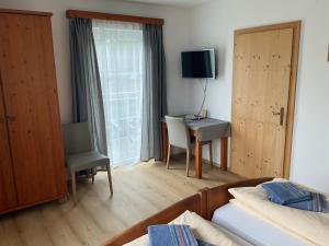 a bedroom with a bed and a desk with a television at Gästezimmer am Bauernhof in Behamberg