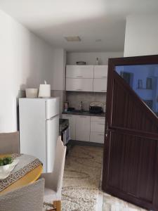 a kitchen with a refrigerator and a table and a door at Avdic Guest House in Makljenovac