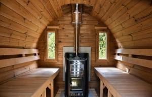 a fireplace in a wooden cabin with two benches at The Cosy Cottage - Comfort Sauna & Hot Tub in Private Garden in Zeewolde