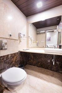 a bathroom with a toilet and a sink and a mirror at Skon Boutique by Orion Hotels in Delhi