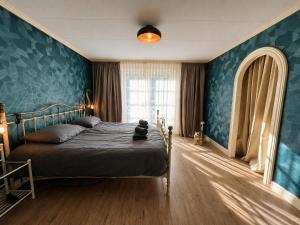 a bedroom with a bed and a blue wall at The Cosy Cottage - Comfort Sauna & Hot Tub in Private Garden in Zeewolde +66 photos