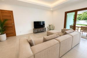 a living room with a couch and a tv at Tropical villa - Private pool - 3 bedrooms in Ko Phangan