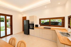a kitchen with white walls and a black refrigerator at Tropical villa - Private pool - 3 bedrooms in Ko Phangan