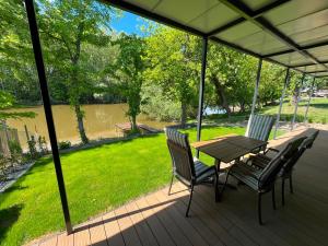 a table and chairs on a porch with a view of a river at MAX Dunaj in Trstice