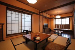 a living room with a table and two windows at Ryokan Yamanoyu in Minamioguni