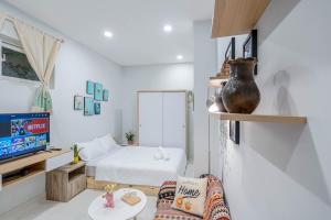 a small white room with a bed and a tv at LalaHouse Pasteur in Ho Chi Minh City