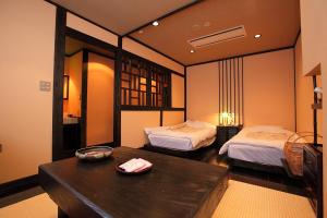 a room with two beds and a table in a room at Ryokan Yamanoyu in Minamioguni