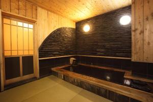 a bath tub in a room with a brick wall at Ryokan Yamanoyu in Minamioguni