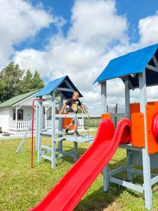 a man playing on a slide at a playground at Domki Bałtyku Szept in Darłowo