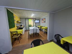 a dining room with tables and yellow tables and chairs at Pousada uberaba in Uberaba