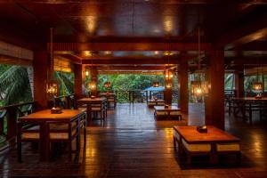 a restaurant with wooden tables and chairs in a room at TSG Aura in Neil Island