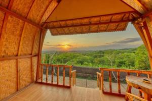 a room with a balcony with a view of the sunset at The Penida Angmas View in Nusa Penida
