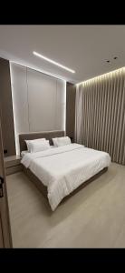 a bedroom with a large bed with white sheets at Elite Stay in Buraydah