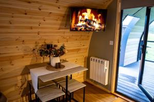 a room with a table and a fire in the wall at The Fox at Snowhill Glamping in Scorton