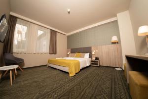ein Hotelzimmer mit einem Bett und einer gelben Decke in der Unterkunft Lignum Hotel in Miskolctapolca + 37 Fotos