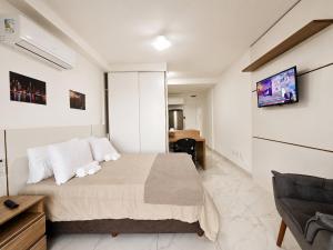 a bedroom with a bed and a tv on a wall at Studio moderno no centro próximo a Academia e Cave in Juiz de Fora