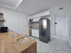 a kitchen with a stainless steel refrigerator and a counter at Studio moderno no centro próximo a Academia e Cave in Juiz de Fora