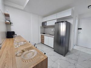 a kitchen with a counter and a stainless steel refrigerator at Studio moderno no centro próximo a Academia e Cave in Juiz de Fora