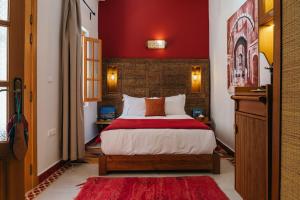 a bedroom with a bed with a red wall at Riad Mazal Mogador in Essaouira