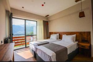 a hotel room with two beds and a large window at Lens Design Hotel in Kazbegi