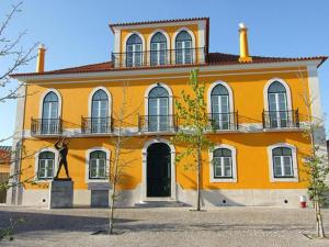 a yellow house with a balcony on top of it at Casa Baptista II in Marinha Grande