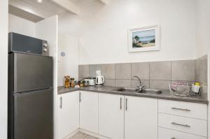 a kitchen with white cabinets and a stainless steel refrigerator at Jacobsdaller #1 in Jacobs Bay