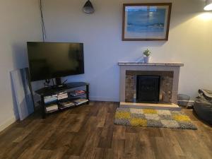 a living room with a fireplace and a flat screen tv at Farrihy Hill House in Doonbeg