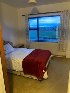 a bedroom with a bed and a large window at Farrihy Hill House in Doonbeg +3 photos