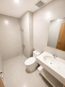 a white bathroom with a toilet and a sink at VSIP Executive Living in Hòa Lợi (1)