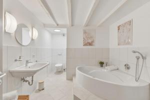 a white bathroom with a tub and a sink at Scharnhäusle 6 - wunderschönes Apartment mit Balkon in Ostfildern