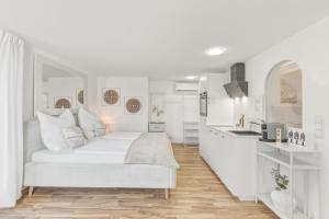 a white bedroom with a bed and a kitchen at Scharnhäusle 6 - wunderschönes Apartment mit Balkon in Ostfildern