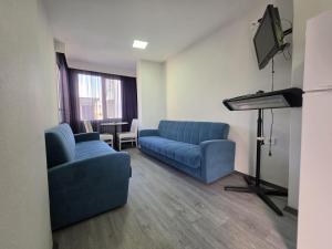 a living room with two blue couches and a piano at ALİBABAM APART OTEL in Kuşadası