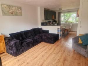 a living room with a black couch and a kitchen at 78 Atlantic Reach in Newquay