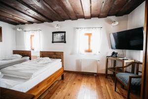 a bedroom with two beds and a flat screen tv at Hotel Dvor Jezersek Brnik in Cerklje na Gorenjskem